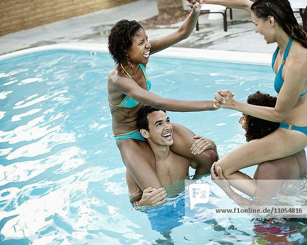 Eine Gruppe junger Männer und Frauen im Schwimmbad am Ende eines heißen Tages.