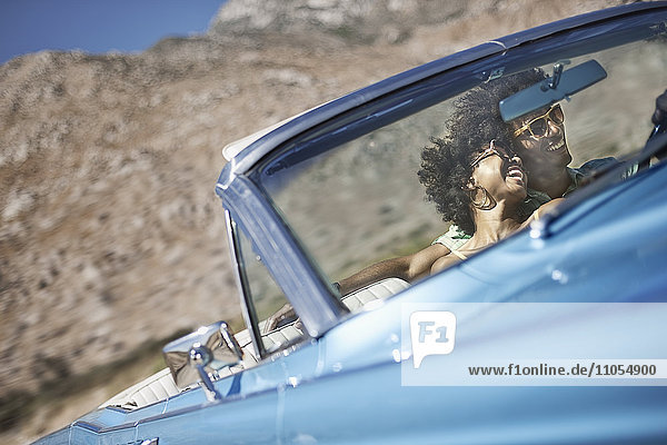 A young couple  man and woman in a pale blue convertible on the open road