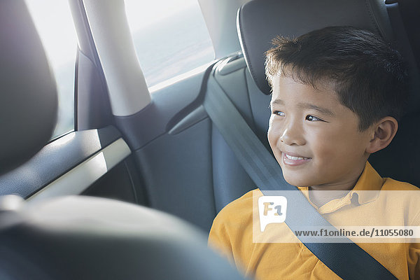 A boy sitting in a car looking out of the window.