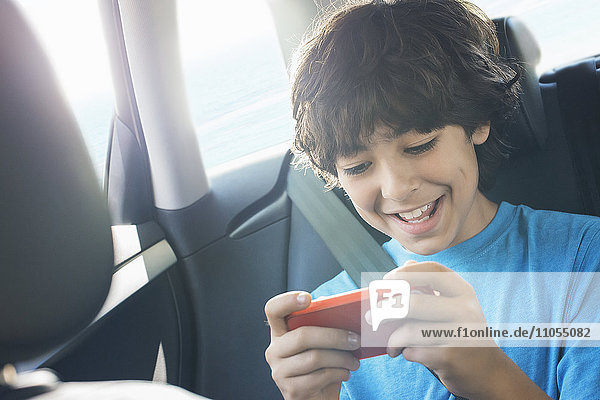 Ein Junge sitzt in einem Auto und benutzt ein tragbares Spieltablett.