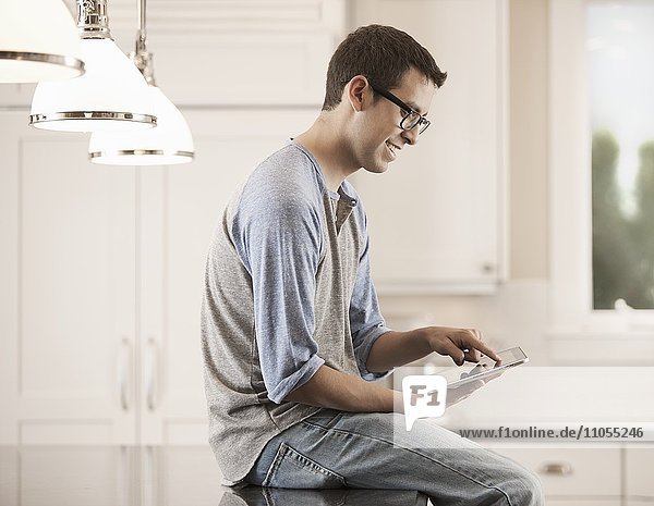 Ein Mann sitzt zu Hause und benutzt ein digitales Tablett.