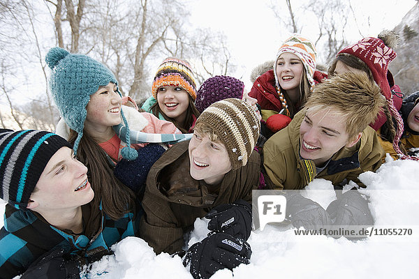 A group of friends  young boys and girls  lying in the snow.