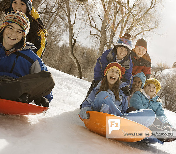 A group of children  boys and girls  riding on sledges on the snow.