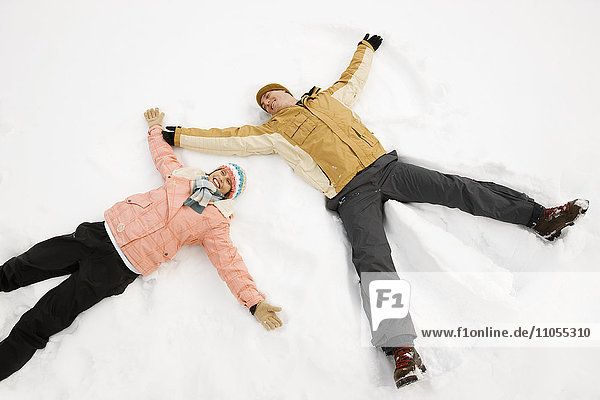 Zwei Menschen  ein Mann und eine Frau  die im Schnee liegen  bilden Schnee-Engelformen.