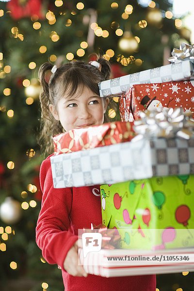 Ein Mädchen mit einem Haufen Weihnachtsgeschenke.