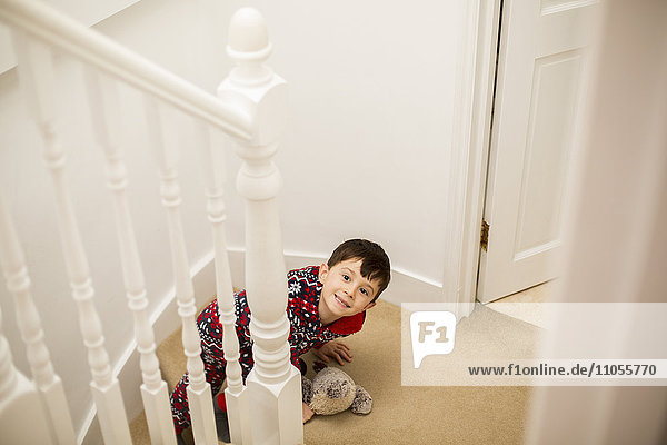 Ein Junge sitzt auf der Treppe  schaut nach oben und grinst.