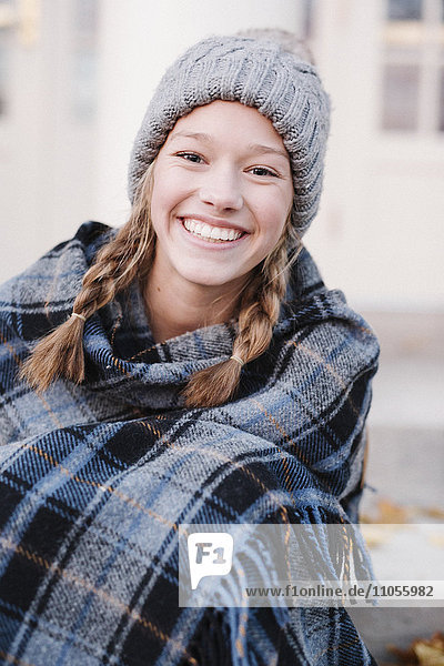 Ein Teenager-Mädchen in Schottenkaro-Schal und Wollmütze im Winter im Freien.