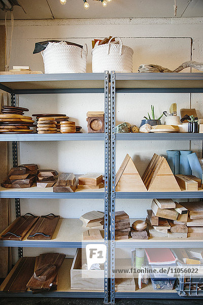 Regale in einer Drechslerwerkstatt und eine Ausstellung glatter Holzklötze und runder Teller und Schalen.