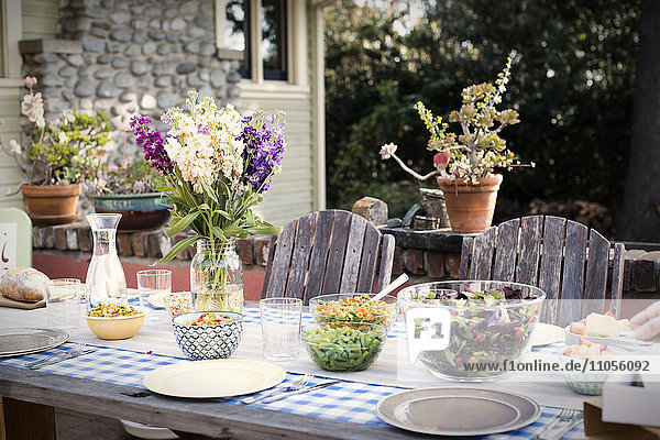 Ein gedeckter Tisch für eine Mahlzeit im Freien in einem Garten.