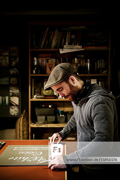 Ein Mann  der in seiner Werkstatt an einem Schild arbeitet.