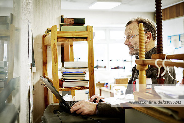 A man using a laptop computer on a bookbinding business.