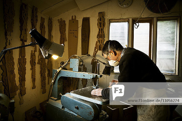 Ein Mann,  der in der Werkstatt eines Möbelherstellers arbeitet und eine Maschinensäge benutzt.