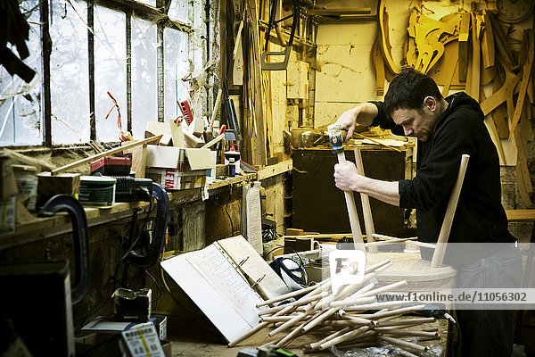 Ein Mann  der in der Werkstatt eines Möbelherstellers arbeitet. Stühle von Windsor.