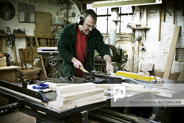 Ein Mann  der in der Werkstatt eines Möbelherstellers arbeitet.