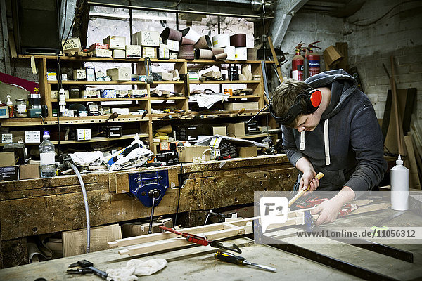 Ein Mann  der in der Werkstatt eines Möbelherstellers arbeitet.