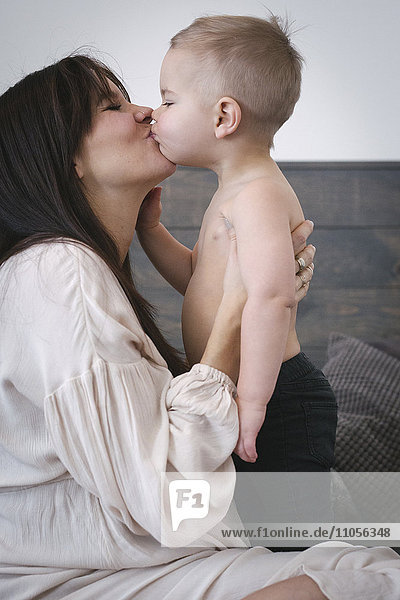 Eine hochschwangere Frau küsst ihren kleinen Sohn.