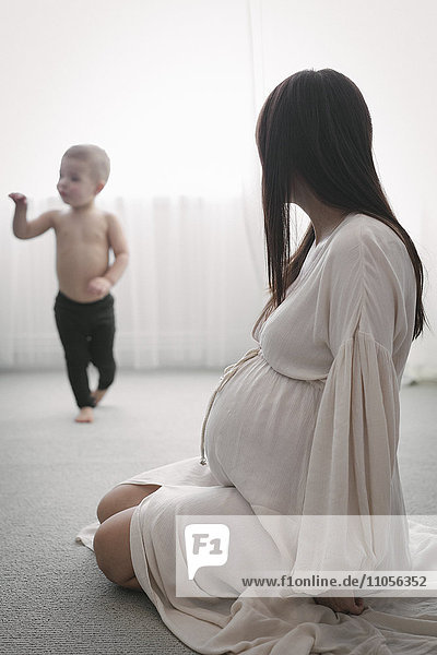 Eine hochschwangere Frau spielt mit ihrem kleinen Sohn.