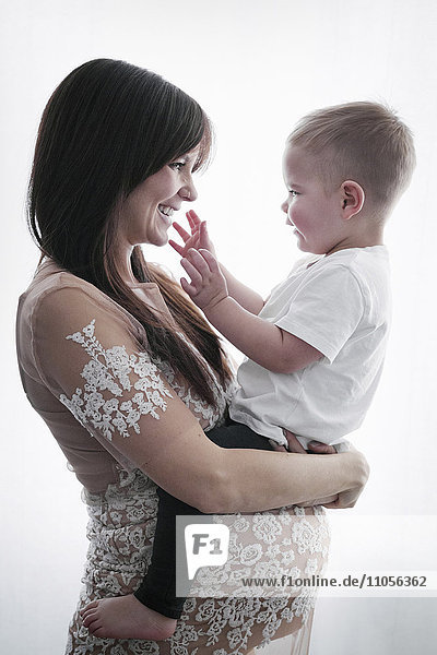 Eine schwangere Frau hält ihren kleinen Sohn im Arm.