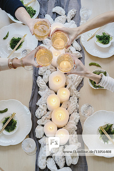 Draufsicht auf vier Personen  die sich eine Mahlzeit teilen  Sushi-Platten und ein gedeckter Tisch für ein Festmahl.