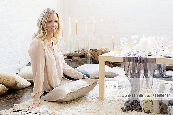 Eine Frau sitzt an einem Tisch,  der für ein Festessen gedeckt ist,  mit brennenden Kerzen und Gläsern mit Wein.