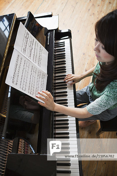 Young woman playing on a grand piano in a rehearsal studio.