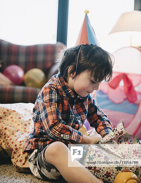 Ein Junge packt auf seiner Geburtstagsfeier seine Geschenke aus.