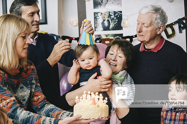 Eine Familie versammelte sich,  um den Geburtstag eines einjährigen Mädchens zu feiern. Ein Kuchen mit vielen Kerzen.