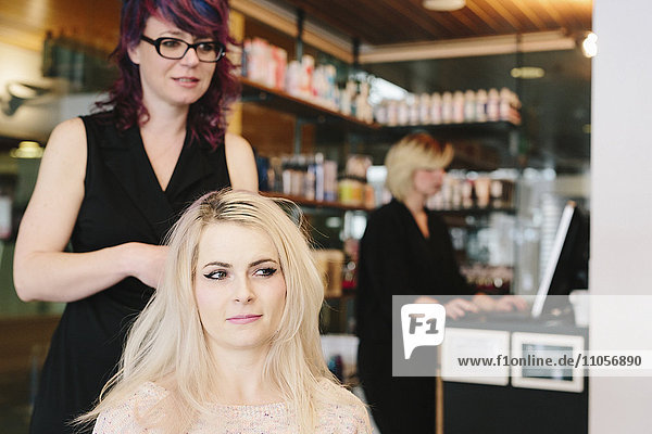 Ein Friseur und eine Kundin  eine junge Frau mit langen blonden Haaren  in einem Friseursalon.