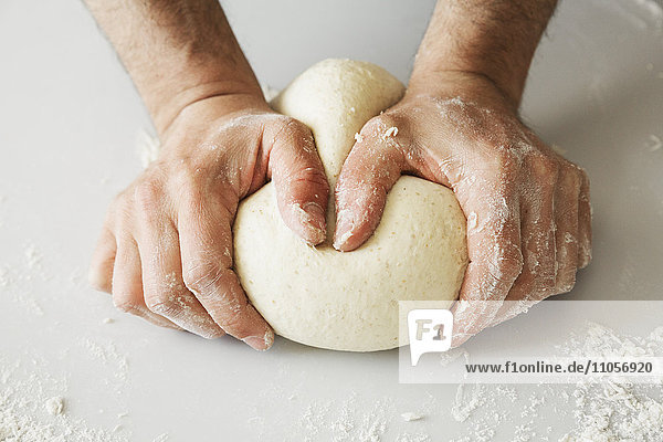 Nahaufnahme eines Bäckers  der Brotteig zu einer Kugel knetet und formt.