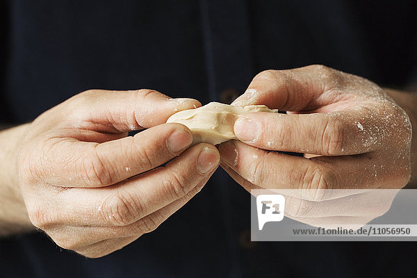 Nahaufnahme eines Bäckers  der Stücke frischer Hefe in den Händen hält.