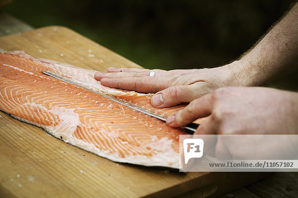 Close up of a chef filleting a fresh salmon.