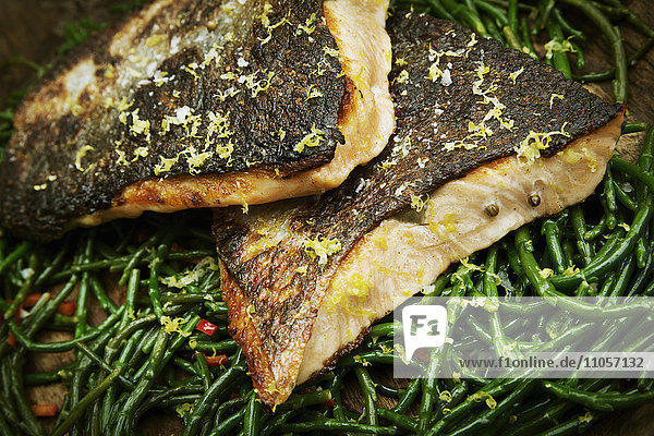 Close up of grilled fish fillets with crispy skin on a bed of samphire.