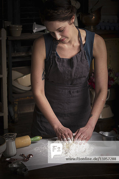 Valentinstag beim Backen  junge Frau steht in einer Küche und bereitet Teig für Kekse vor.