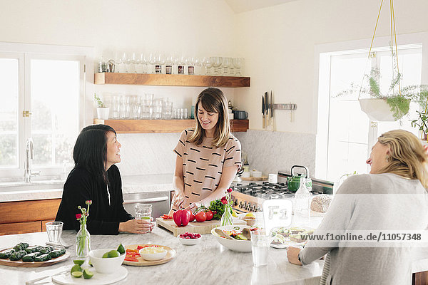 Drei Frauen unterhalten sich und bereiten gemeinsam das Mittagessen vor.