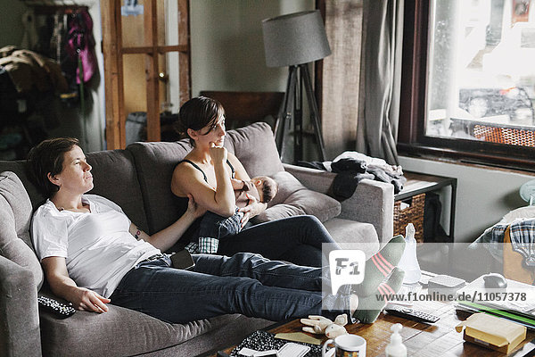 Zwei Frauen  ein Paar zu Hause  auf dem Sofa sitzend  eine stillen ein Baby.