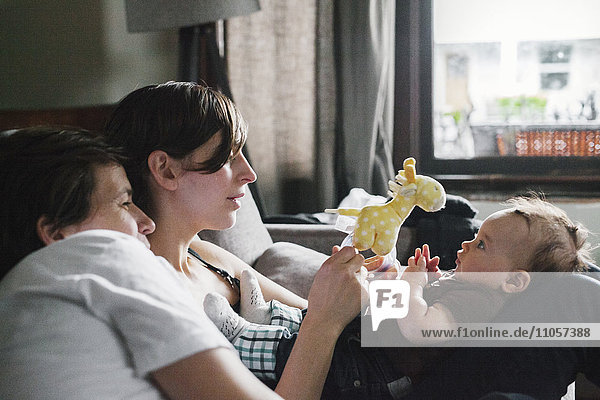 A same sex couple  two women playing with their 6 month old baby girl.