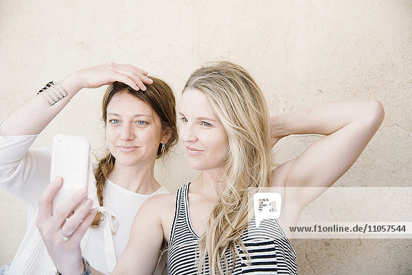Zwei lächelnde Frauen beim Selfie mit dem Handy.