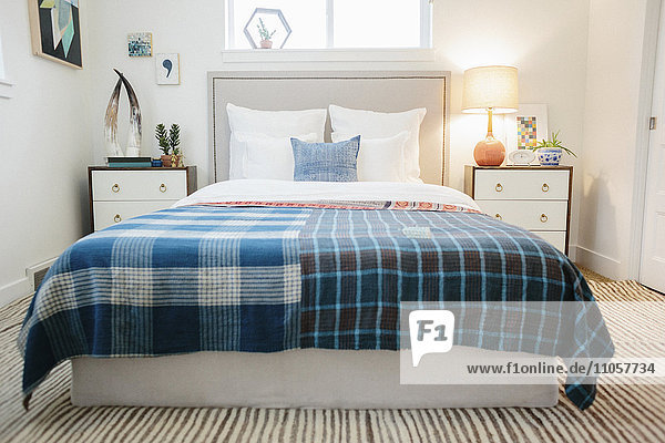 A bedroom in an apartment with a double bed with a colourful checked bed cover