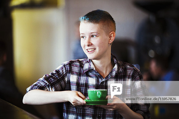 Spezialisiertes Kaffeehaus. Eine junge Person  die eine Tasse Kaffee trägt.