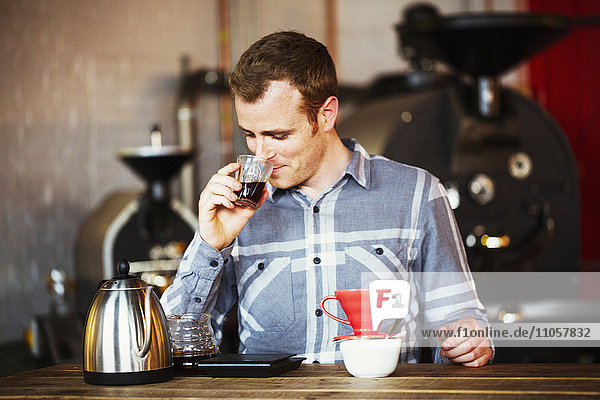 Spezialisiertes Kaffeehaus. Ein Mann  der mit Hilfe eines Filterpapiers Kaffee brüht und ihn trinkt.