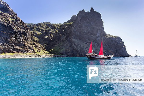 Segelboot mit roten Segeln einer kleinen Bucht bei Los Gigantes  Santiago del Teide  Teneriffa  Kanarische Inseln  Spanien  Europa