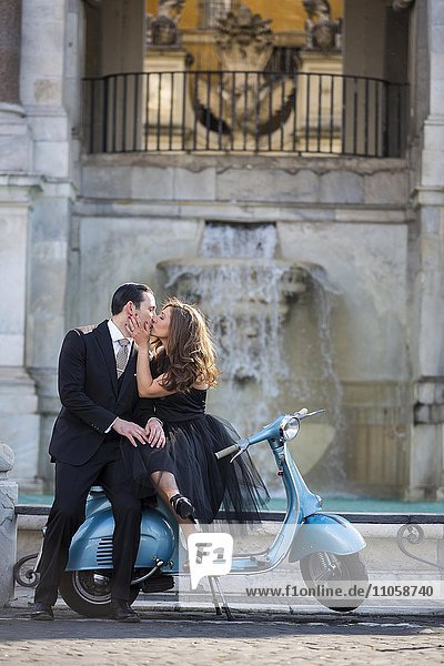 Couple kissing while sitting on a vespa scooter. Fontana dell'Acqua Paola  Il Fontanone  Gianicolo Hill  Janiculum Hill  Rome  Italy  Europe