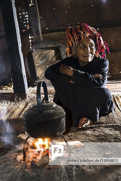 Old woman in the kitchen kettle on an open fire place in the lodge mountain tribe or mountain people Pa-O or Pa-Oh or Pao or Black Karen or Taungthu or dew-soo ethnic minority near Kalaw Shan State Myanmar Asia