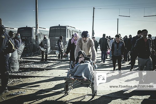 Flüchtlinge und alte Frau im Rollstuhl am Grenzzaun  Flüchtlingslager Idomeni  Grenze zu Mazedonien  Griechenland  Europa