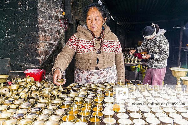 Eine Frau ordnet Butterlampen in einem Tempel in Boudha  Kathmandu  Nepal  Asien