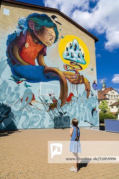 junges Mädchen betrachtet Graffiti mit Comic-Motiv an einer Hauswand  Würzburg  Bayern  Deutschland  Europa