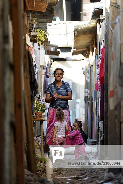 Frau  ca 40  mit Enkelkindern in einer engen Gasse zwischen Baracken eines Armenviertels  Favela 21 de Abril  Sao Paulo  Brasilien  Südamerika