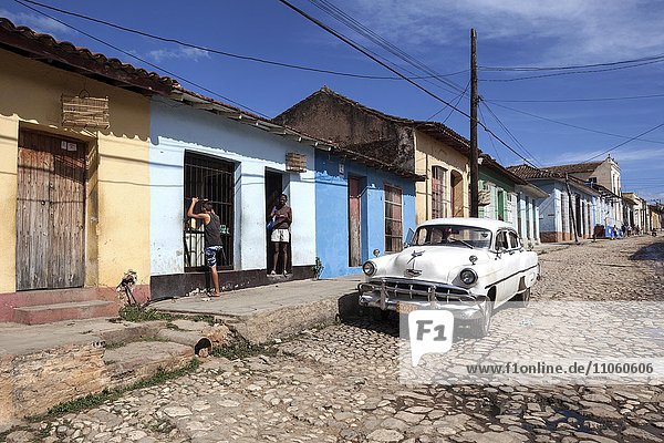 Straßenszene  typische Straße mit Kopfsteinpflaster  bunte Häuser und Oldtimer  historische Altstadt  Trinidad  Provinz Sancti Spiritus  Kuba  Nordamerika