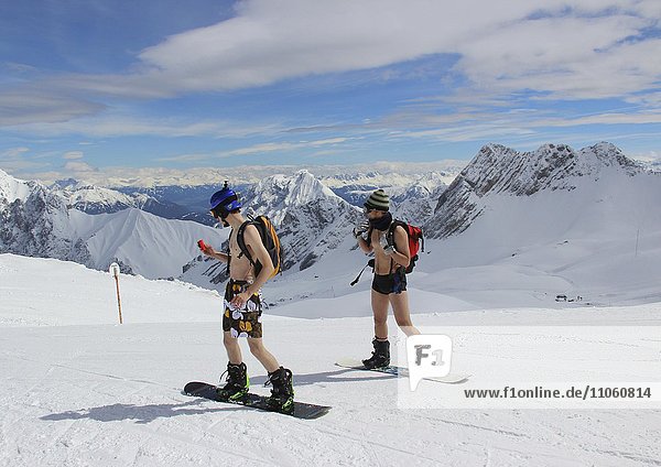 Two men are snowboarding in shorts and no shirt on the Zugspitzplatt  mountain Zugspitze  Bavaria  Germany  Europe