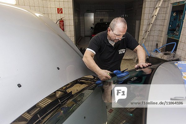 Wechseln  einsetzen der Frontscheibe an einem PKW in einer Kfz-Werkstatt für Autoglas  Düsseldorf  Nordrhein-Westfalen  Deutschland  Europa